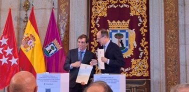 Two men shaking hands in front of flags at a formal event.