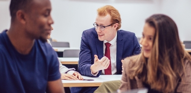 A group of students engaged in a discussion in a classroom setting.