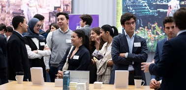 A group of young adults engaging in conversation at a professional networking event.