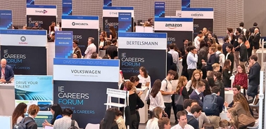 A crowded career fair with various company booths and attendees engaging with recruiters.