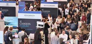 A busy career fair with multiple company booths and attendees engaging in discussions.