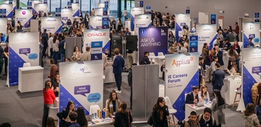 A busy career fair with numerous informational booths and attendees interacting.