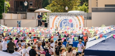 A lively outdoor festival with colorful banners and people enjoying the event.