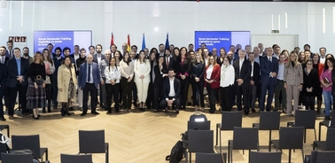 A large group of people posing for a photo in a conference room with banners in the background.