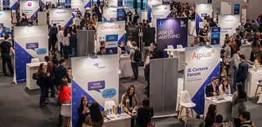 A busy career fair with many booths and attendees networking.