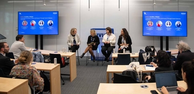 A panel discussion featuring multiple speakers in a modern conference room setting.