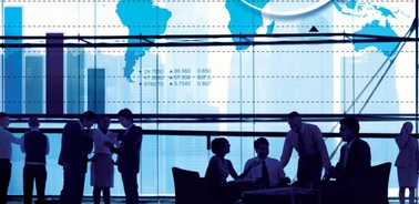 A silhouette of business professionals interacting with a backdrop of world maps and data charts.