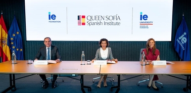 A formal meeting at the Queen Sofía Spanish Institute with three individuals seated at a table.
