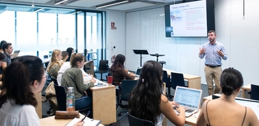 A classroom setting where a teacher is delivering a lecture to a group of attentive students.