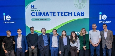 A group of people standing in front of a banner celebrating the winners of the Climate Tech Lab at IE University.