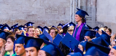 A graduate stands out among a crowd of fellow graduates celebrating their achievement.