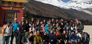 A large group of people gathered in front of a beautiful mountain backdrop.