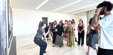 A group of people listening to a presentation in an art gallery.