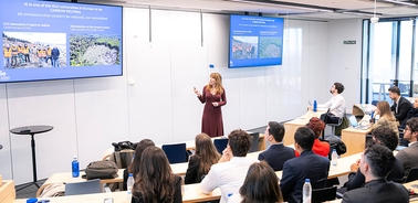 A woman presents to a group of attentive individuals in a modern classroom setting.