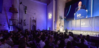 A speaker presents at a university event in front of an audience.