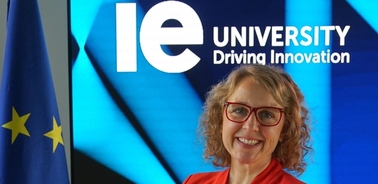 A woman smiling in front of an IE University banner with the European Union flag