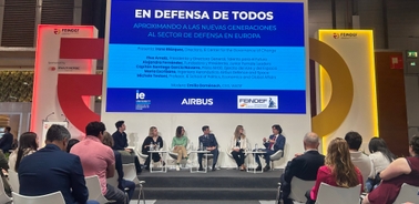 A panel discussion taking place at a conference with multiple speakers and an audience.