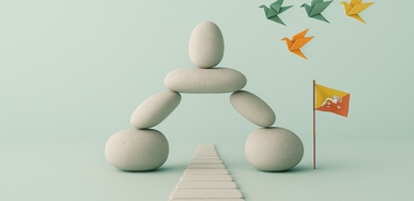 A whimsical arrangement of stones creating a figure with origami birds flying above and a small flag.