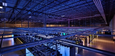 A view of a large data center with rows of servers illuminated by colorful lights.