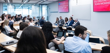 A panel discussion taking place in a classroom setting with an audience present.