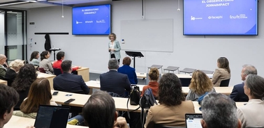 A person is giving a presentation in front of an audience in a modern conference room.