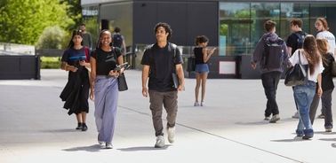 A group of students walking on a university campus on a sunny day.