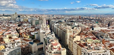 A panoramic view of a city with numerous buildings under a partly cloudy sky.