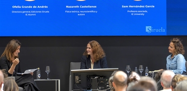 A panel discussion featuring three women discussing various topics on stage.