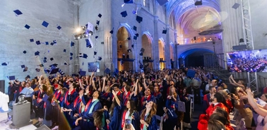 A lively graduation ceremony with students throwing their caps in celebration.