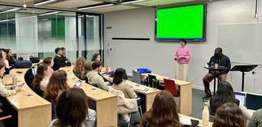 A classroom setting with a speaker presenting to an audience.