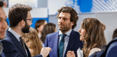 Three business professionals engaged in a conversation at a networking event.