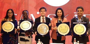 A group of five individuals proudly displaying their awards at a ceremony.