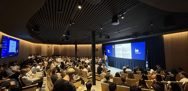 A large audience assembled in a modern auditorium for a presentation.