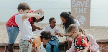 A group of children working together to clean up the beach while promoting environmental awareness.