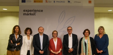 A group of seven people standing in front of a sign that reads 'experience market' at an indoor event.