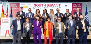 A group of professionals posing together with thumbs up at the South Summit event.