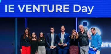 A group of people celebrating at IE Venture Day with a trophy.