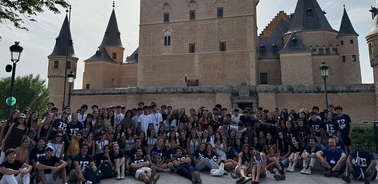 A large group of students gathering in front of a historic castle.