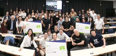 A group of people in a classroom holding banners with smiling faces.