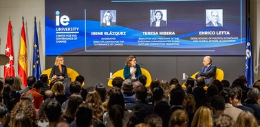 A discussion featuring three speakers on stage at an academic event.