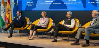 Four individuals sitting on stage during a panel discussion at a conference, facing an audience.