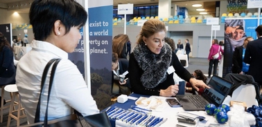 A woman is presenting information at an exhibition while another woman listens attentively.