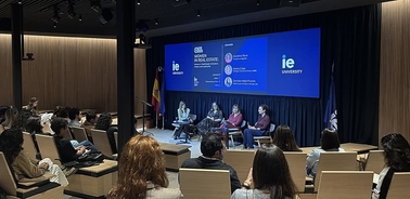 A panel discussion at IE University with audience members in a modern auditorium setting.