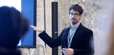 A man is giving a presentation in front of a screen.