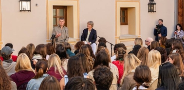 A speaker addressing an audience in an outdoor setting.