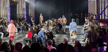 A fashion show taking place in a stylish venue with an audience watching the models walk down the runway.