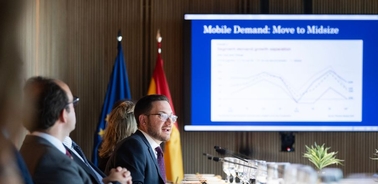 A business meeting taking place with a presentation on mobile demand trends displayed on a screen.
