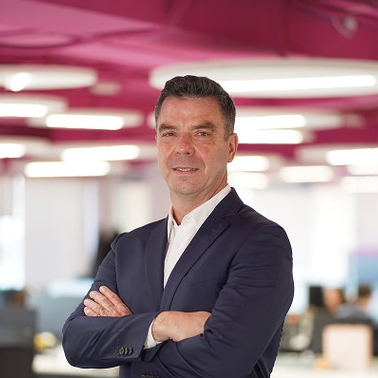 A man in a suit stands confidently in a modern office environment.