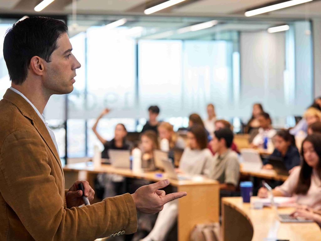 A speaker presents in front of an engaged audience in a classroom setting.