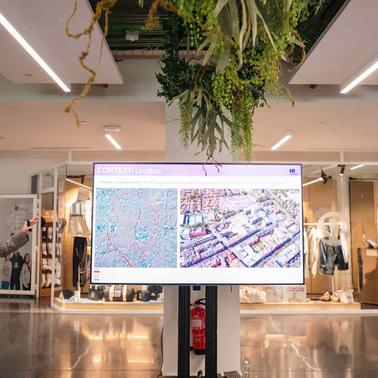 A presenter is giving a talk with a digital screen showing maps at an event.